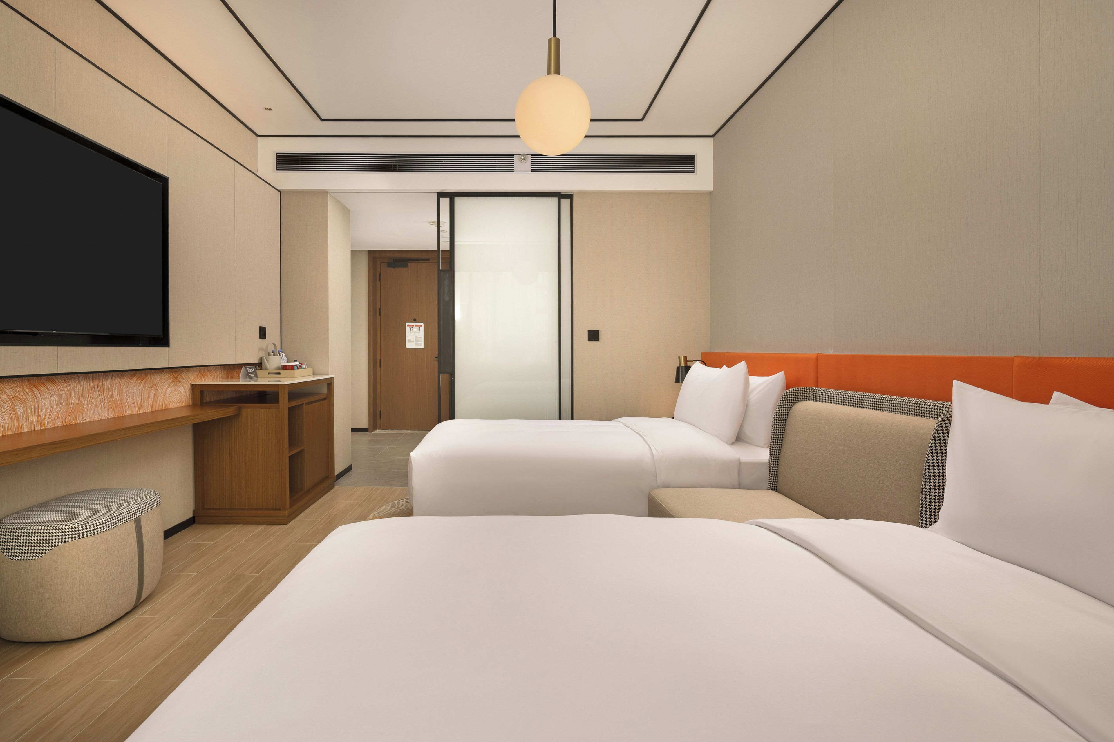A hotel room with a large bed, a desk, a television, and a wardrobe.