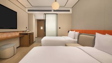 A hotel room with a large bed, a desk, a television, and a wardrobe.