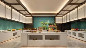 Une cuisine moderne dotée d’un îlot central, de meubles blancs et d’un pare-feu turquoise.