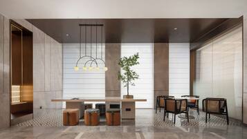 A modern interior with a central table, seating, and a hanging light fixture.