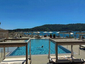 Ein Poolbereich mit einer Person, Liegestühlen und Sonnenschirmen.