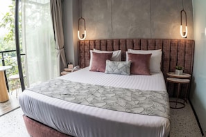 A modern bedroom with a large bed, two bedside tables, and a view of greenery outside. - Glow Medellín (Medellín)