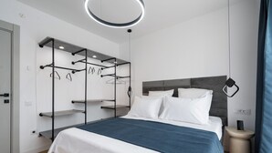 A modern bedroom with a bed, a built-in wardrobe with multiple shelves, a bedside table, and a hanging light fixture. - AviStay Bratianu Old Town (București)