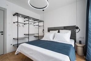 A modern bedroom with a bed, a built-in wardrobe with multiple shelves, a bedside table, and a hanging light fixture. - AviStay Bratianu Old Town (București)