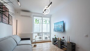 A modern living room with a grey sofa, a TV mounted on the wall, and a herringbone wooden floor. - AviStay Bratianu Old Town (București)