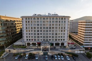 Hotel de diverses plantes amb entrada central, zona d'aparcament al davant i entorn urbà circumdant.