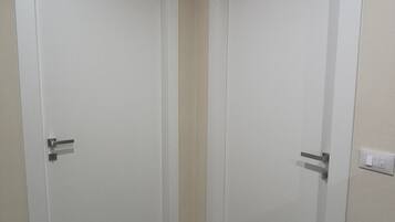 A hallway with two white doors, a light switch, and a wall socket.