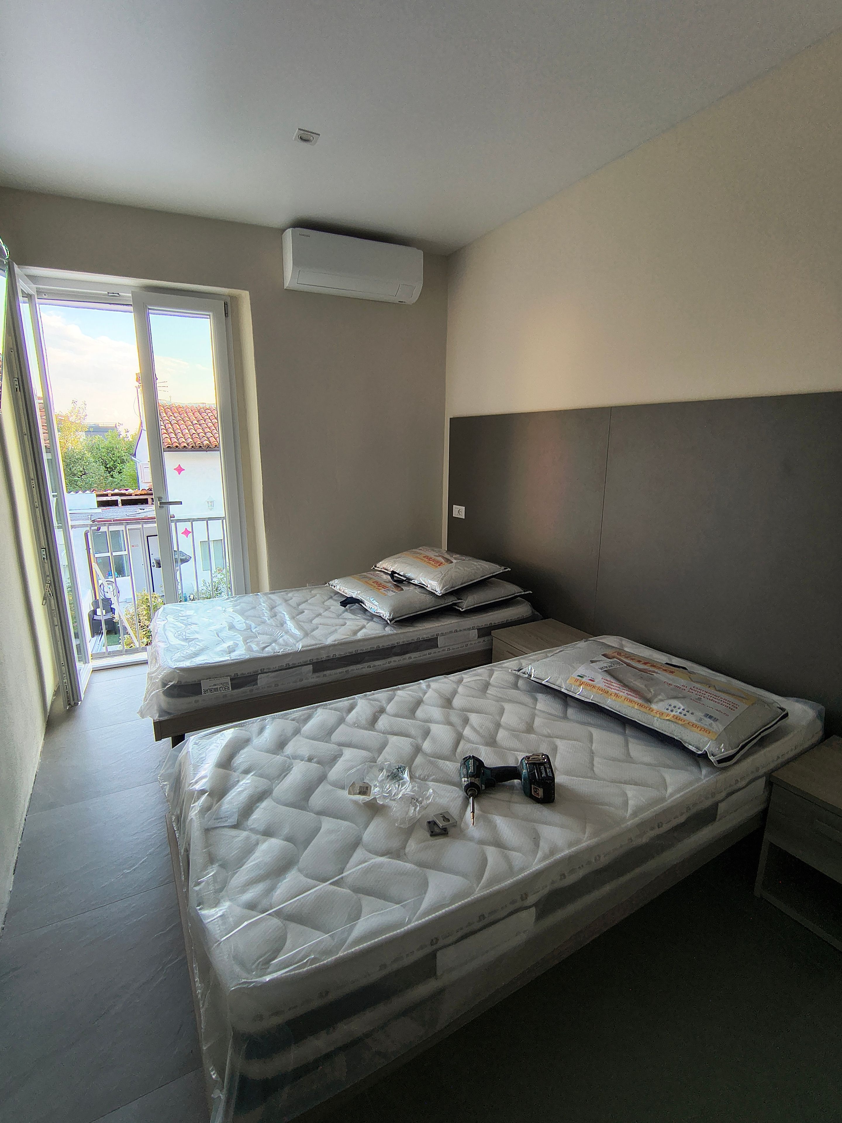 Una camera da letto con due letti, un balcone e un condizionatore d'aria.