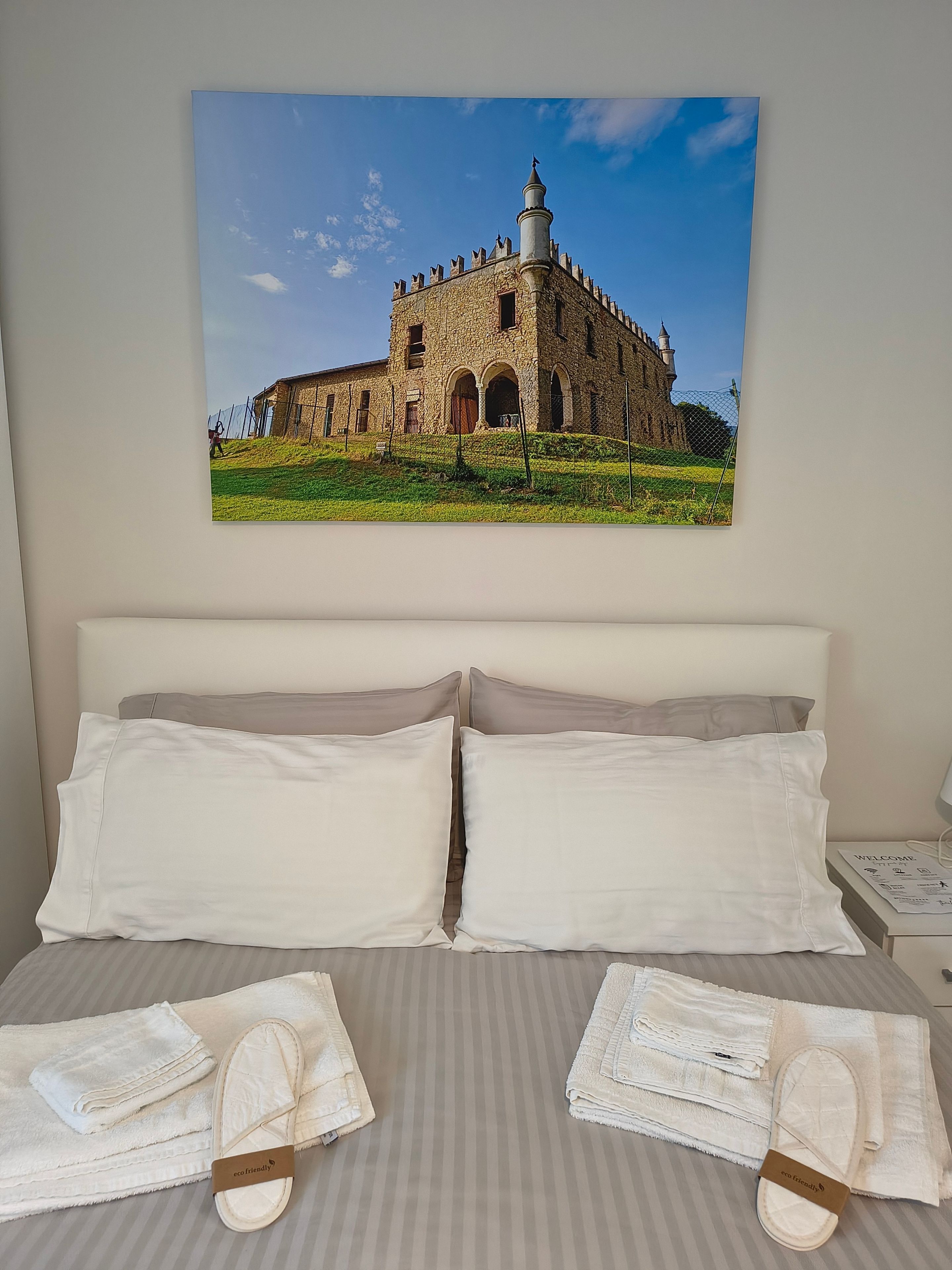 Una camera d'albergo con un letto, cuscini e asciugamani.