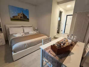 A hotel room with a bed, bedside table, and a view of a building through the window. - Twin Room 'Mavi' (Cellatica)