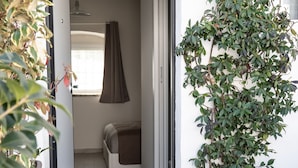 Een deuropening naar een kamer met een bed, een hanglamp en een potplant.