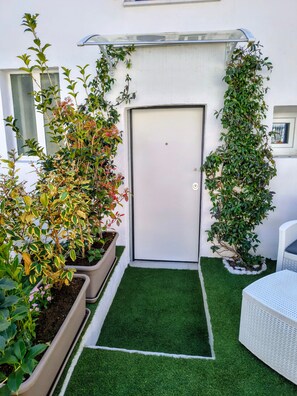 A small outdoor area with artificial grass, a white door, and potted plants. - Twin Room 'Mavi' (Cellatica)