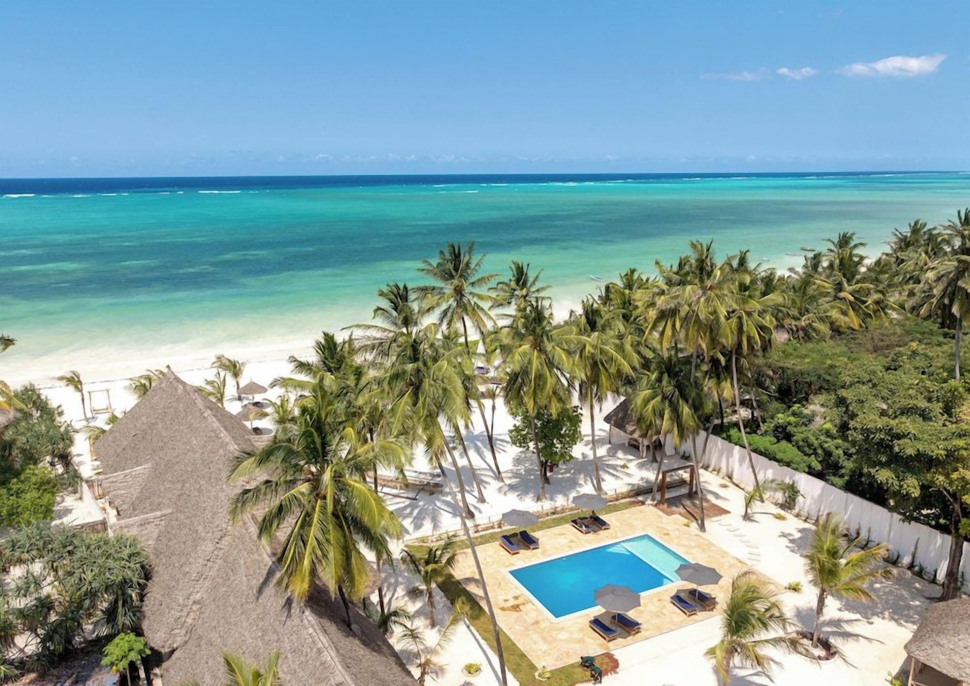 A resort with a pool, palm trees, and a beach view.