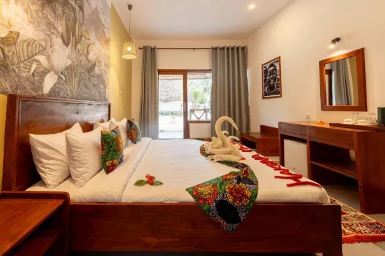 A hotel room with a bed, a desk, a chair, a mirror, and a window.