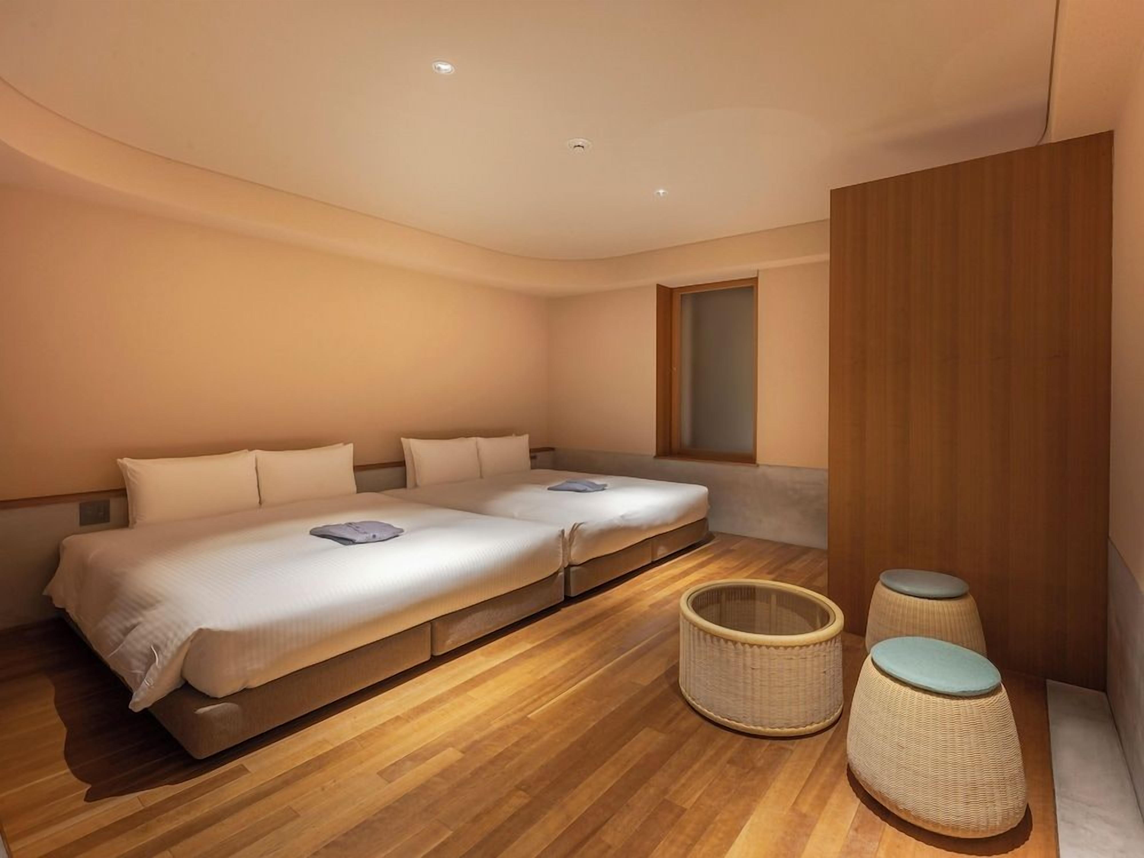 A hotel room with a large bed, a small table, and a window.
