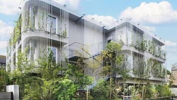 A modern building with vertical garden elements, balconies, and a curved facade.