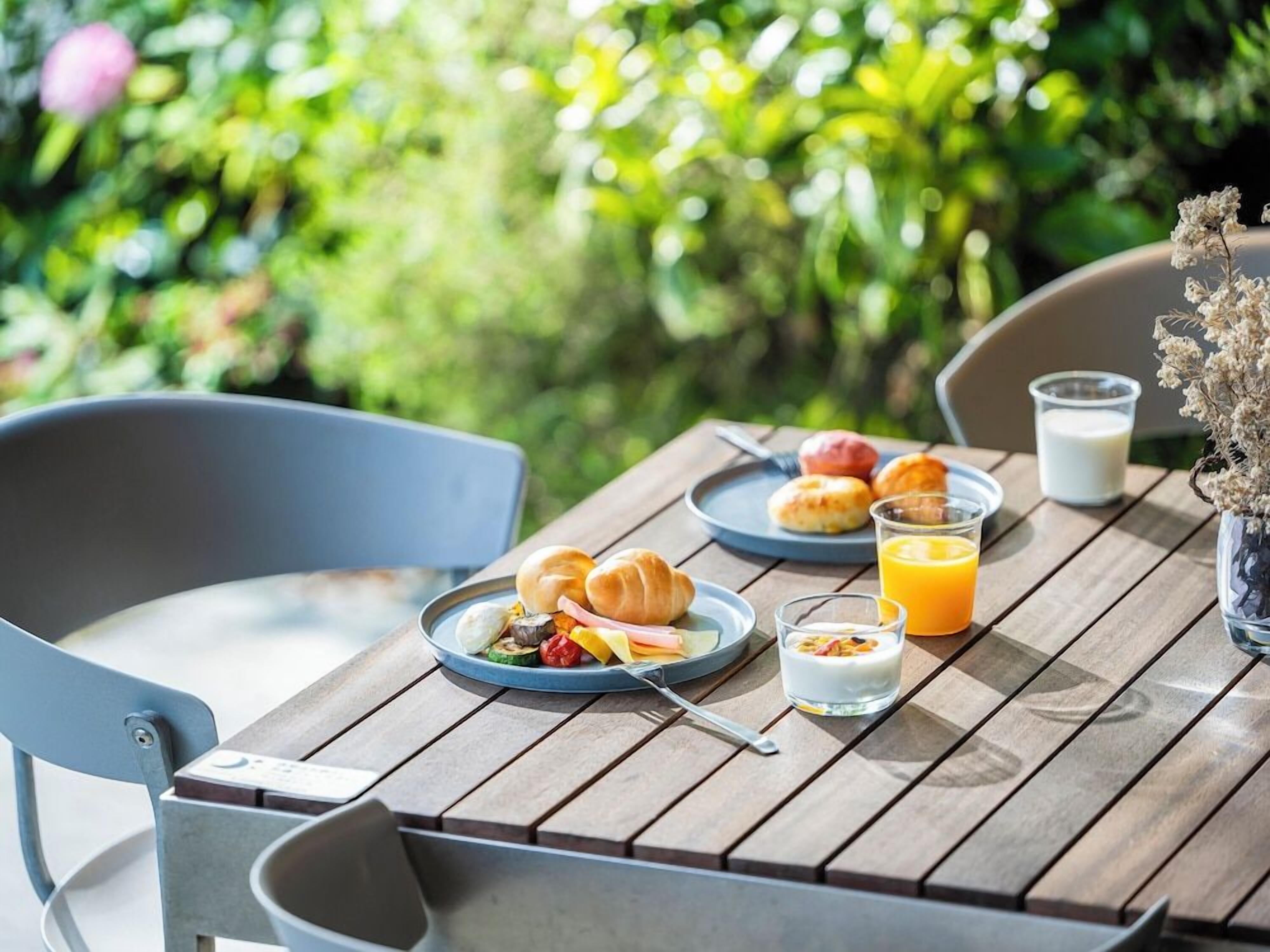 A wooden table with breakfast items including croissants, a glass of orange juice, and a plate of food.