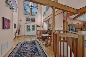 Ein geräumiges Interieur mit einer Holztreppe, einem Essbereich mit Tisch und Stühlen sowie einer Küche mit Schränken und Geräten.