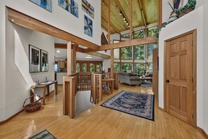 Un interior espacioso con vigas de madera, una escalera y vistas al exterior.