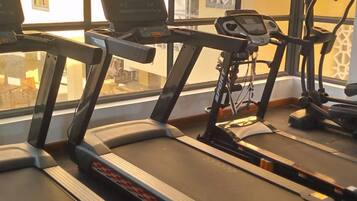 Una cinta de correr con pantalla digital y panel de control, ubicada en una habitación con ventana.