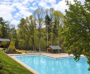 A swimming pool with a wooden deck and a gazebo, surrounded by trees and a grassy area. - Big Mountain view cabin rental in Walnut Mountain. Pet Friendly, hot tub and pool table (Ellijay)