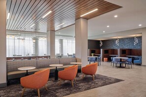 Un moderno vestíbulo de hotel con zonas de estar, una recepción y un comedor.