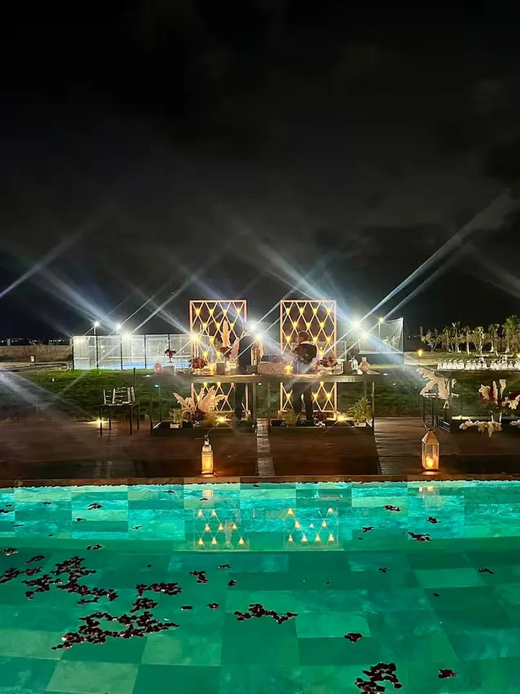 Un área de piscina con una estructura lumínica geométrica y cielo despejado.