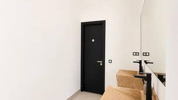 Une salle de bain moderne avec un grand miroir, une porte noire et des carreaux de couleur beige.