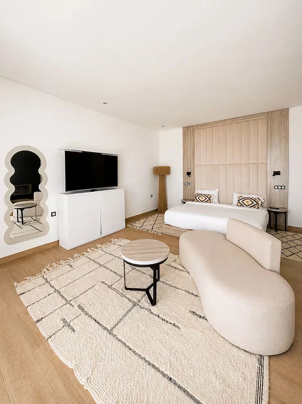Un salon moderne avec un téléviseur à écran plat, un canapé, une table basse et un tapis à motifs.