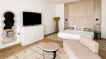 Un salon moderne avec un téléviseur à écran plat, un canapé, une table basse et un tapis à motifs.