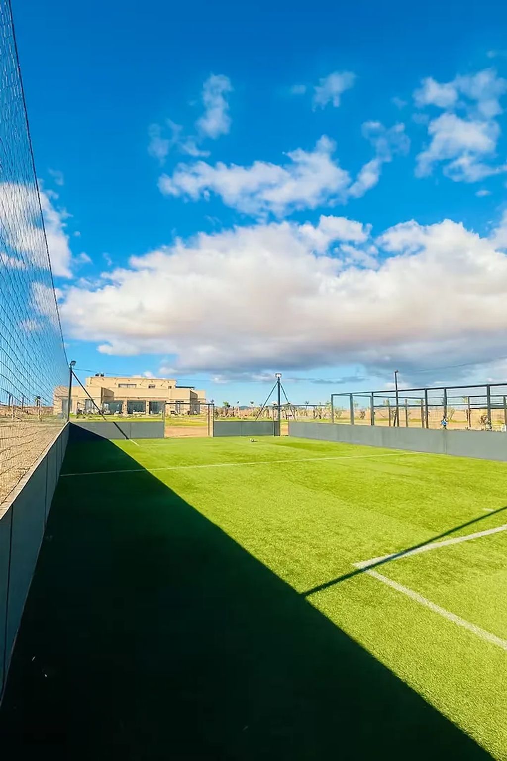 A sports field with a goalpost, a fence, and a clear sky.