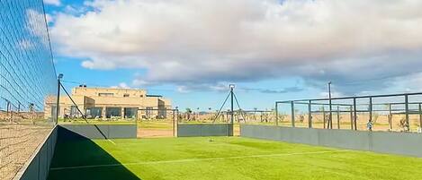 A sports field with a goalpost, a fence, and a clear sky.