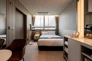 A compact hotel room with a bed, bedside table, chair, and a desk with a chair. - My Me Hotel (Seoul)