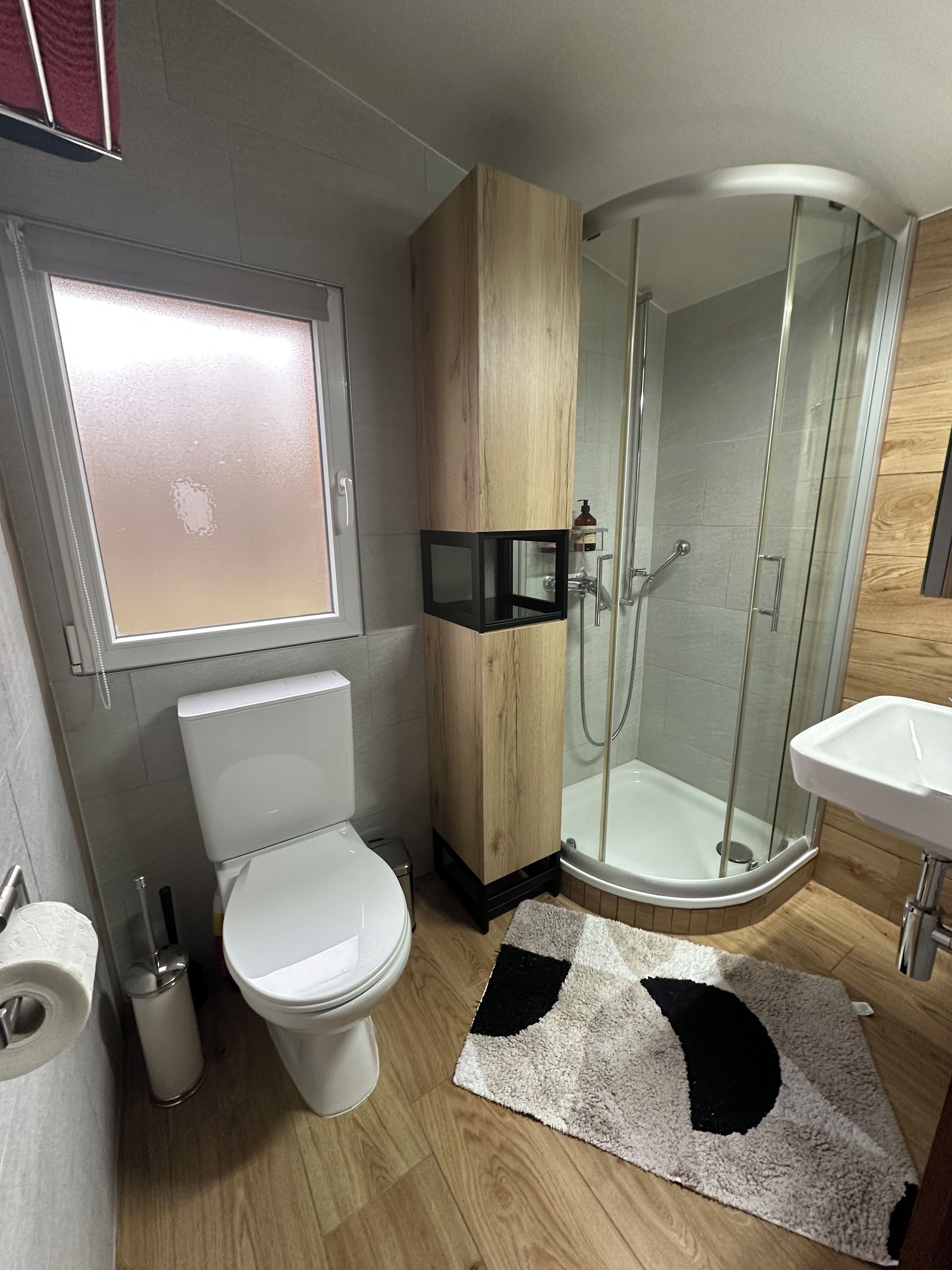 A modern bathroom with a toilet, a glass-enclosed shower, and a sink.