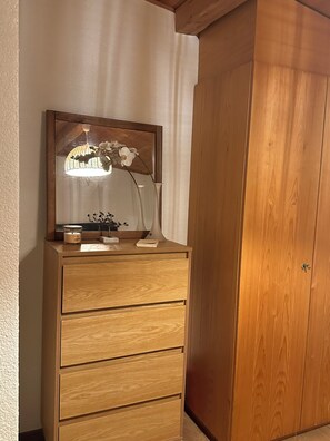 Une commode en bois avec un miroir, une bougie et un vase rempli de fleurs.