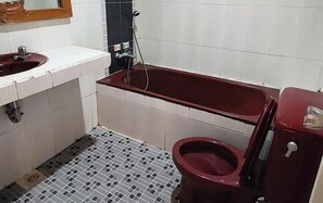 A bathroom with a red toilet, a white sink, and a shower area. - Hotel Semeru Bogor (Bogor)