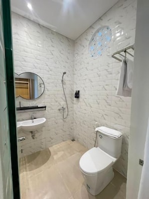 Un baño con inodoro blanco, lavamanos y ducha.
