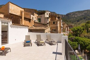 Una terraza en la azotea con sillones de descanso y vistas a un pueblo en la ladera.