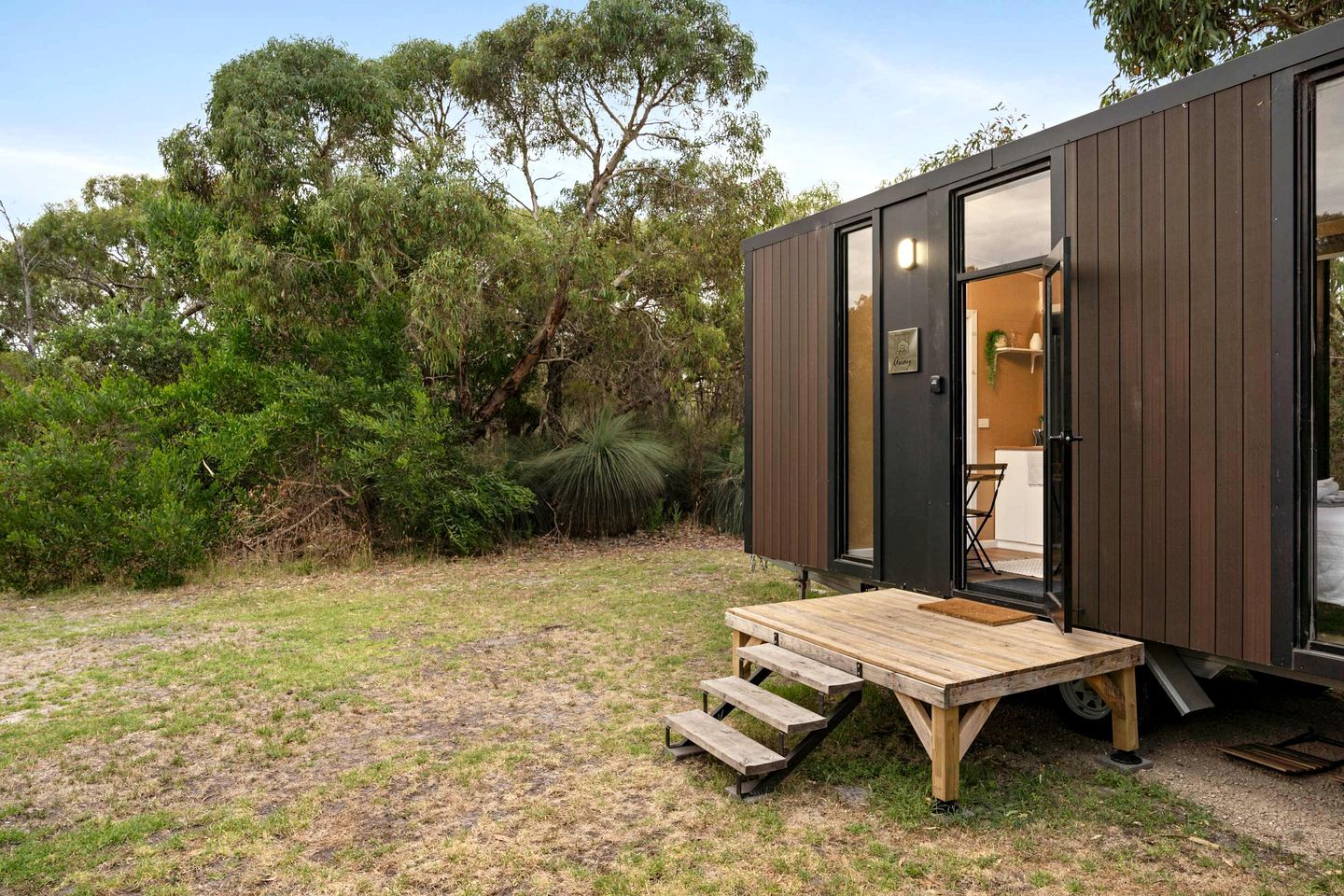 A modern, compact cabin with a wooden deck and a door leading to an interior space.