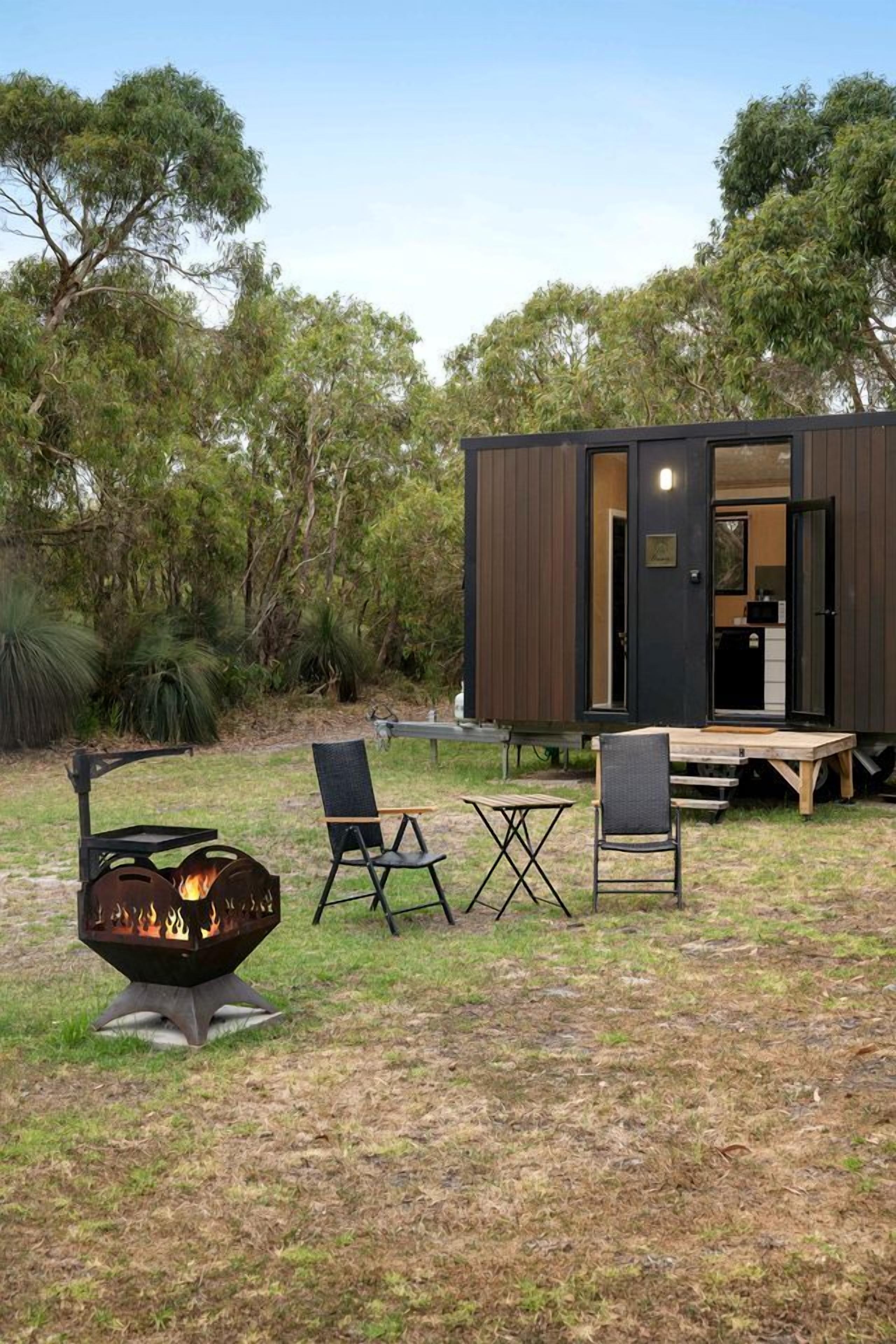 Uma área externa moderna para relaxar, com lareira, assentos e deck de madeira.
