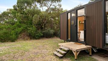 A modern, compact cabin with a wooden deck and a door leading to an interior space.