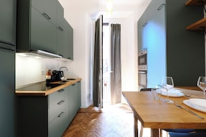 A modern kitchen with a wooden countertop, built-in appliances, and a dining area with a table set for two. - Contempora - Cozy, Designer Two-Room Apartment for 2 | Monumentale & Sarpi M5 (Milano)