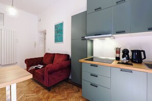 A compact living space with a kitchenette, a red sofa, and a coffee maker. - Contempora - Cozy, Designer Two-Room Apartment for 2 | Monumentale & Sarpi M5 (Milano)
