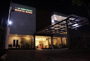 Un hotel moderno con un letrero destacado, un acceso cubierto y un interior bien iluminado.