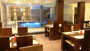 En hotellobby med en pool, ett område för måltider och modern inredning.