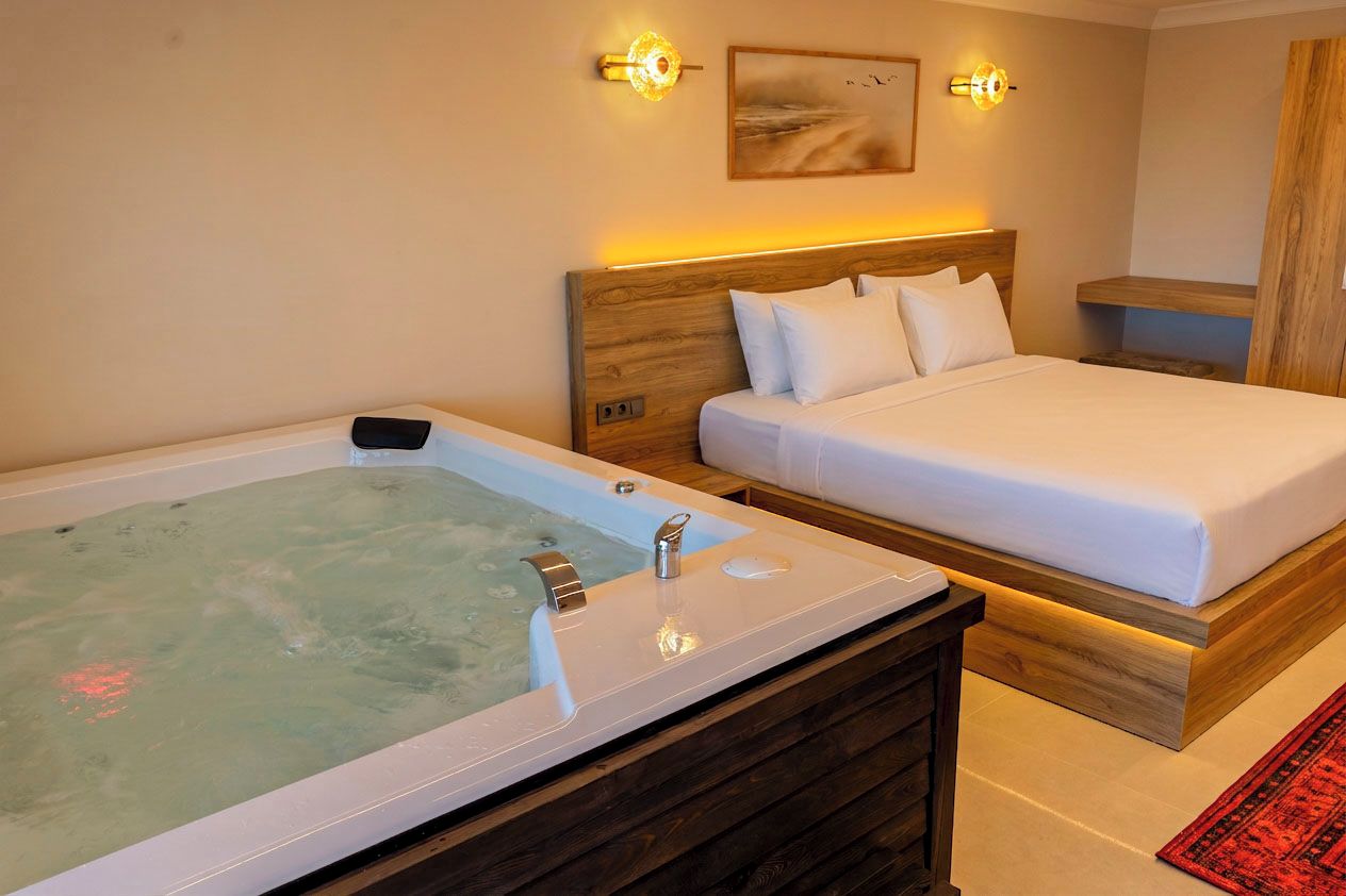 Una habitación con una cama, cabecero de madera, una lámpara de pared y una bañera.