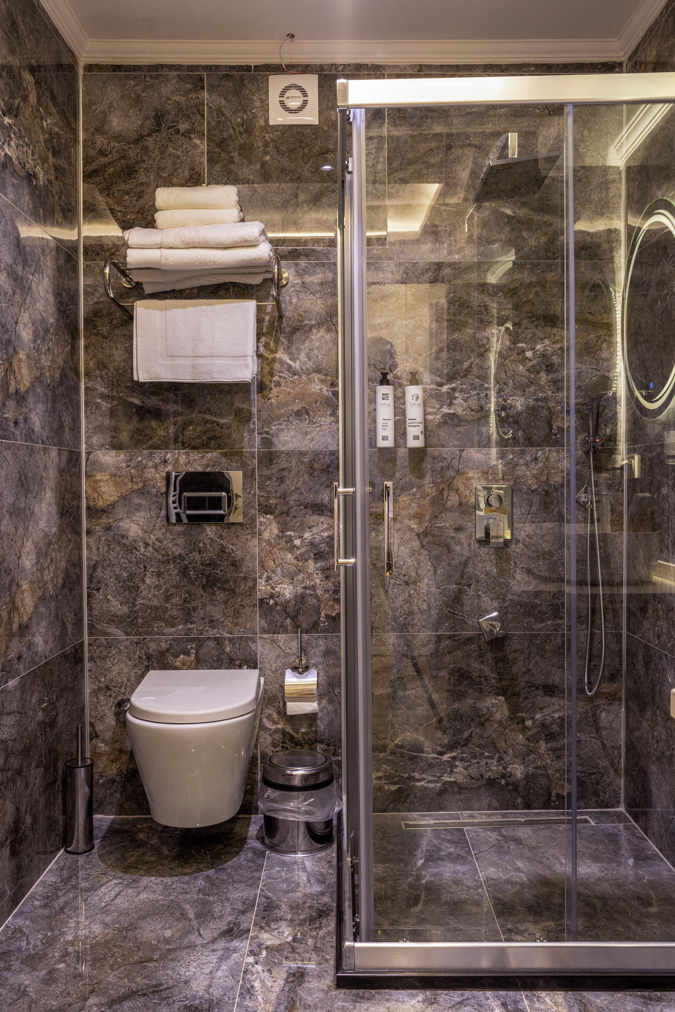 Un baño moderno con ducha de vidrio, inodoro y barra para toallas.