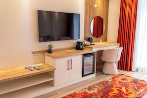 A modern hotel room with a flat-screen TV, a small refrigerator, a coffee machine, a bedside table with a magazine, and a large window with curtains. - CRASSULA URLA (Urla)