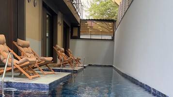 Una piscina interior con sillones de descanso y una zona cubierta.