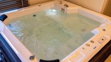 Un jacuzzi con panel de control, un asiento integrado y un ventanal.
